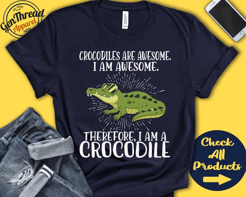 May include: A navy blue t-shirt with a white graphic of a crocodile wearing sunglasses. The text "Crocodiles are awesome. I am awesome. Therefore, I am a crocodile" is printed on the shirt.