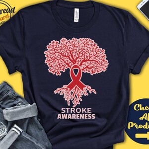 May include: Navy blue t-shirt with a pink and red tree design. The tree is made up of many small pink ribbons and has a large red ribbon at the base. The text "STROKE AWARENESS" is printed below the tree.