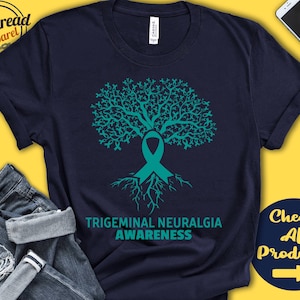 May include: A navy blue t-shirt with a teal tree design and a teal ribbon. The text "Trigeminal Neuralgia Awareness" is printed below the tree.