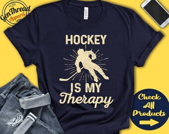 May include: A navy blue t-shirt with a vintage-style graphic of a hockey player and the text "Hockey is my therapy".