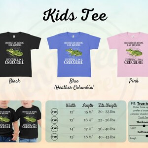 May include: A black, blue, and pink children's t-shirt featuring a crocodile graphic and the text "Crocodiles are awesome. I am awesome. Therefore I am a crocodile." The t-shirt is available in sizes 2-5 years and comes with a size chart showing width, length, and weight.