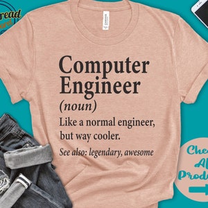Puede incluir: Una camiseta color melocot&oacute;n con la frase "Computer Engineer (sustantivo) Like a normal engineer, but way cooler. See also: legendary, awesome." La camiseta tiene las mangas enrolladas y se muestra con vaqueros y un smartphone.