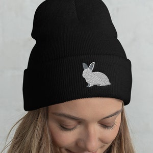 May include: A black beanie with a white embroidered rabbit on the front.