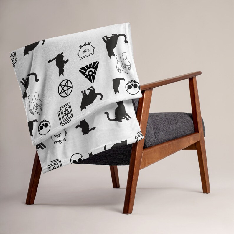 May include: White fleece throw blanket with a black and white pattern of cats, stars, pentagrams, and other occult symbols.