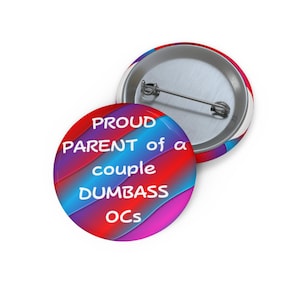 Puede incluir: Un botón redondo con el texto "PROUD PARENT of a couple DUMBASS OCs" en blanco, sobre un degradado de colores rojo, azul y morado. El botón tiene un reverso de alfiler metálico y un borde blanco.