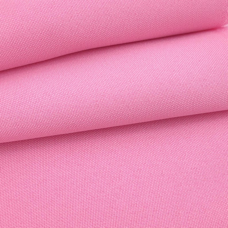 Puede incluir: Primer plano de una tela rosa doblada. La tela tiene una textura tejida y est&aacute; dispuesta en pliegues suaves, creando sombras y profundidad. El color es un rosa vibrante y liso.