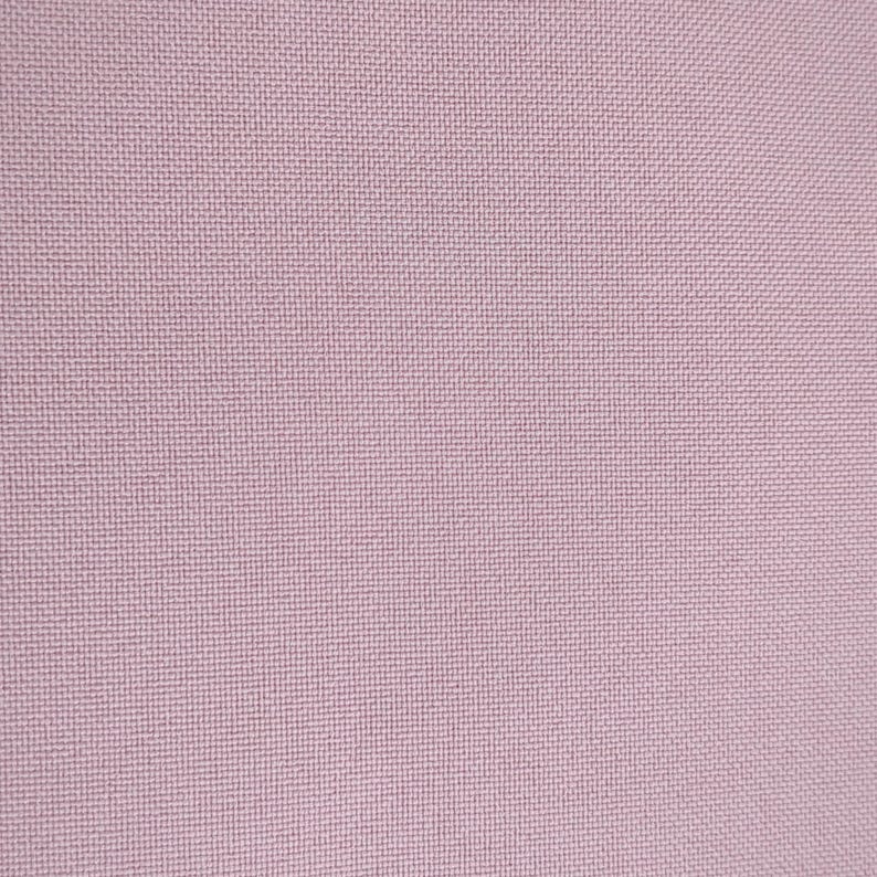 Puede incluir: Primer plano de una tela rosa claro texturizada. El tejido del material es visible, creando un patr&oacute;n similar a una cuadr&iacute;cula. El color es un rosa suave y apagado, con sutiles variaciones de tono en la superficie.