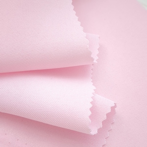 Puede incluir: Primer plano de una pila de tela rosa claro con un tejido texturizado. Los bordes de la tela est&aacute;n cortados con un patr&oacute;n en zigzag. La tela est&aacute; doblada sobre s&iacute; misma, mostrando la textura y las variaciones de color.