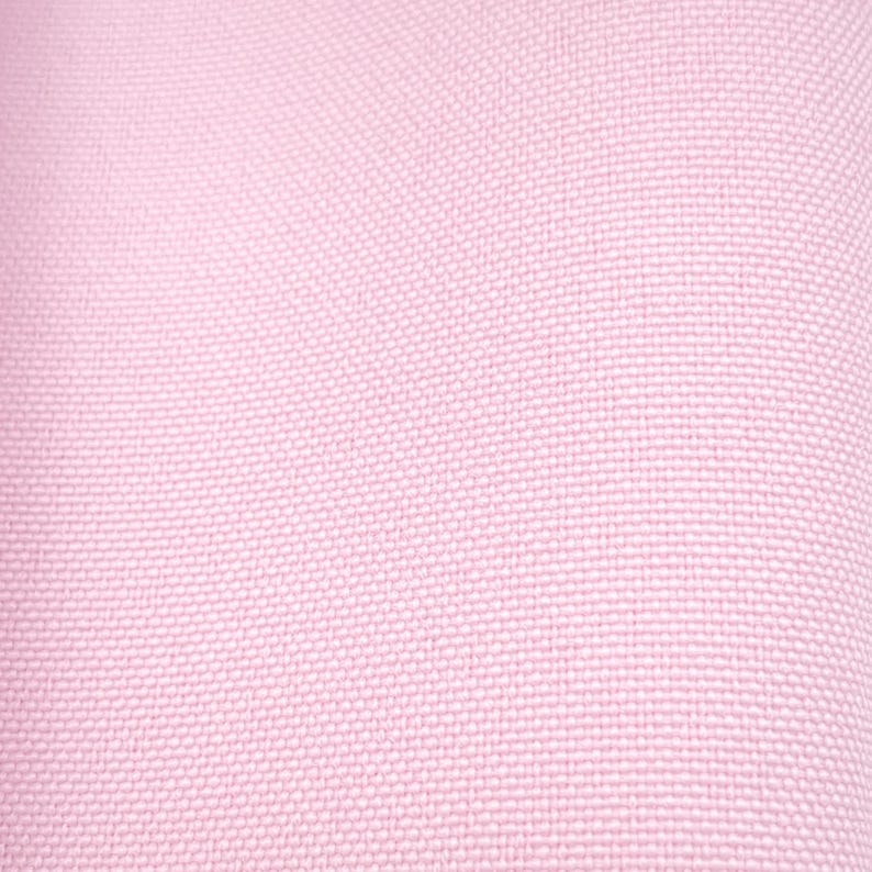 Puede incluir: Primer plano de una tela tejida de color rosa claro. La textura es visible, mostrando un patr&oacute;n de peque&ntilde;os cuadrados espaciados uniformemente. El color es un rosa suave y p&aacute;lido, creando un fondo sutil y texturizado.