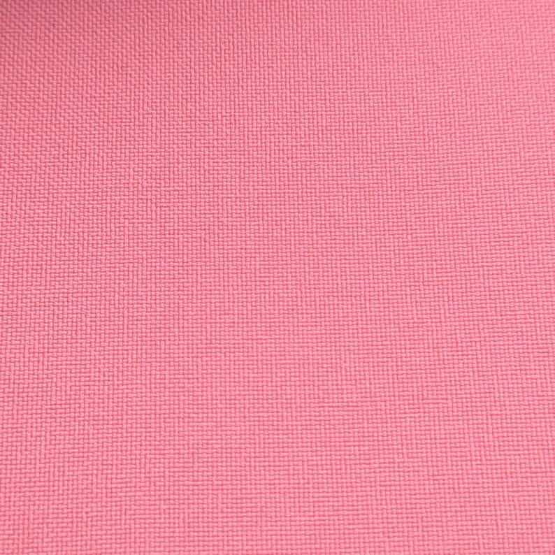 Puede incluir: Primer plano de una superficie rosa texturizada. La superficie tiene un patr&oacute;n tejido o entrecruzado, creando una sutil apariencia de rejilla. El color es un rosa medio s&oacute;lido, que llena el marco.