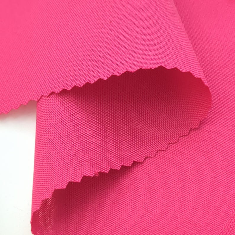 Puede incluir: Primer plano de una tela rosa vibrante con un tejido texturizado. La tela est&aacute; doblada, revelando un borde festoneado. El color brillante y la vista de cerca resaltan la textura y la saturaci&oacute;n del color del material, adecuado para ropa o decoraci&oacute;n del hogar.