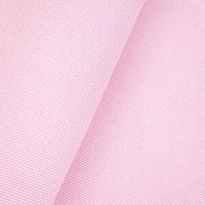 Puede incluir: Primer plano de una tela rosa claro con un tejido texturizado. La tela est&aacute; doblada, creando sombras suaves y resaltando la textura del material. El color es un rosa pastel suave, adecuado para varios proyectos textiles.