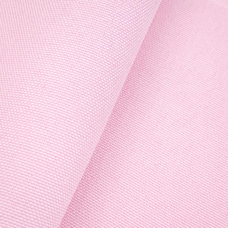 Puede incluir: Primer plano de una tela rosa claro con un tejido texturizado. La tela est&aacute; doblada, creando sombras suaves y resaltando la textura del material. El color es un rosa pastel suave, adecuado para varios proyectos textiles.