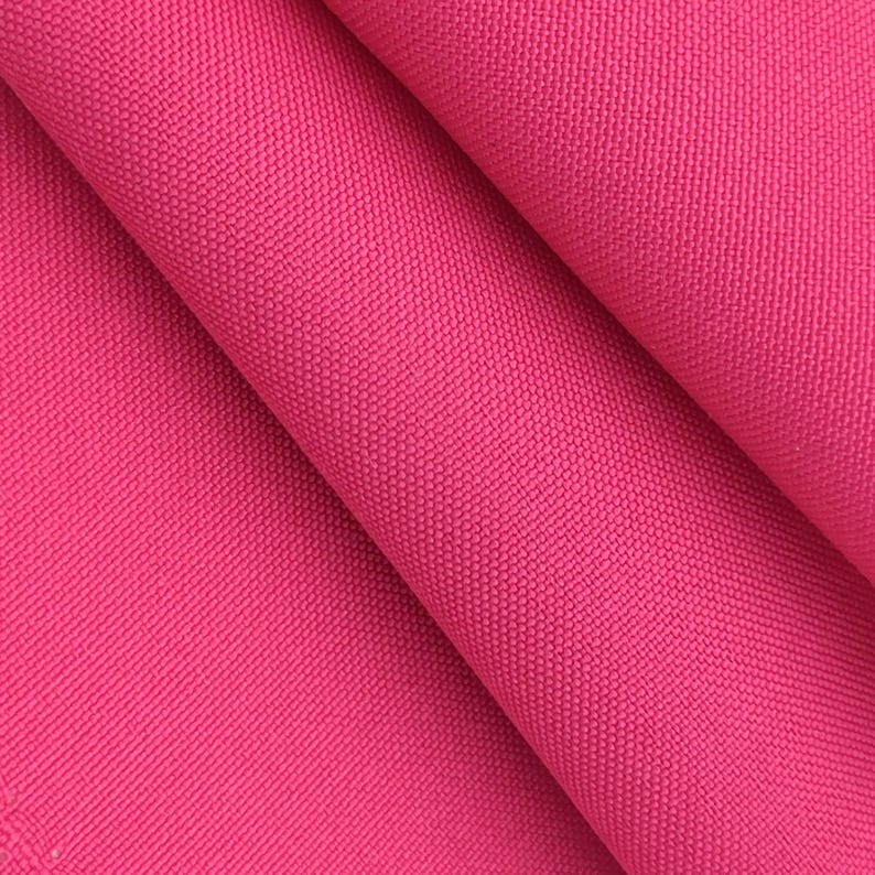 Puede incluir: Primer plano de una tela rosa vibrante con un tejido texturizado. El material est&aacute; doblado, creando sombras y resaltando la textura de la tela. El color brillante sugiere que podr&iacute;a usarse para ropa o decoraci&oacute;n del hogar.
