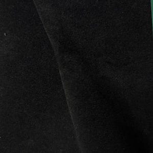 May include: A solid black fabric with a dense, soft, and slightly fuzzy texture. The material is folded, creating a diagonal shadow line that highlights the depth and consistent matte finish of the dark, uniform textile surface.