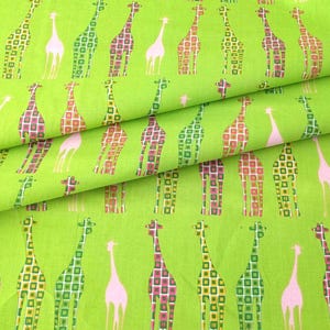 May include: Bright green fabric with a repeating pattern of giraffes in various colors. The giraffes are outlined in white, with pink, green, and orange square patterns filling their bodies. The fabric is folded, showing the texture.
