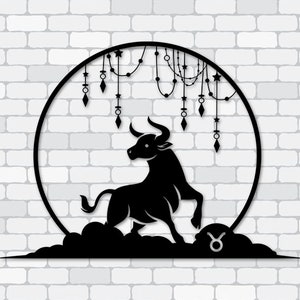 Puede incluir: Arte de pared de metal negro con el signo zodiacal de Tauro. El diseño incluye una silueta de toro dentro de un marco circular, adornada con elementos decorativos colgantes. El toro se encuentra sobre una base en forma de nube, con el símbolo de Tauro visible.