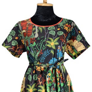 May include: A black short-sleeved dress with a colourful floral print featuring a woman's face and a red trim around the neckline. The dress has a black belt.