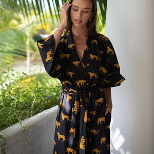 May include: A long black and gold robe with a leopard print. The robe has a tie belt and long sleeves.