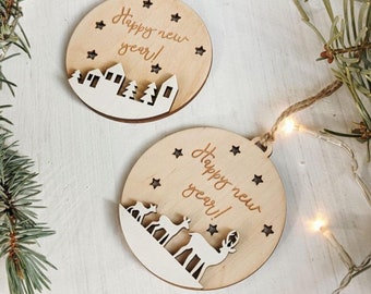May include: Two round wooden ornaments with the text "Happy new year!" and star cutouts. One ornament features a cityscape design, and the other features a reindeer design. Each ornament has a twine loop for hanging.