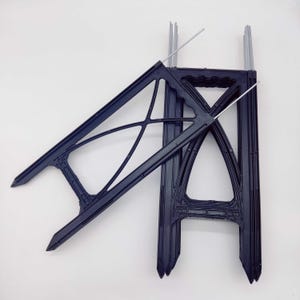 May include: Two black plastic plant supports with metal stakes. The supports are designed to help plants grow upright.