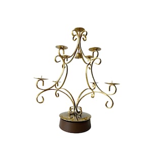 May include: A gold metal candelabra with a bell at the top and five candle holders. The candelabra is on a wooden base.