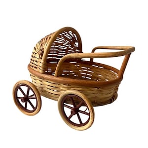 May include: A small wicker doll stroller with brown wheels. The stroller has a wicker handle and a wicker canopy.