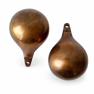 Puede incluir: Dos objetos en forma de lágrima de color bronce. Cada uno tiene un cuerpo redondeado y bulboso con un tallo estrecho y un pequeño agujero en la parte superior. Los objetos tienen una superficie lisa y reflectante y parecen ser de metal.
