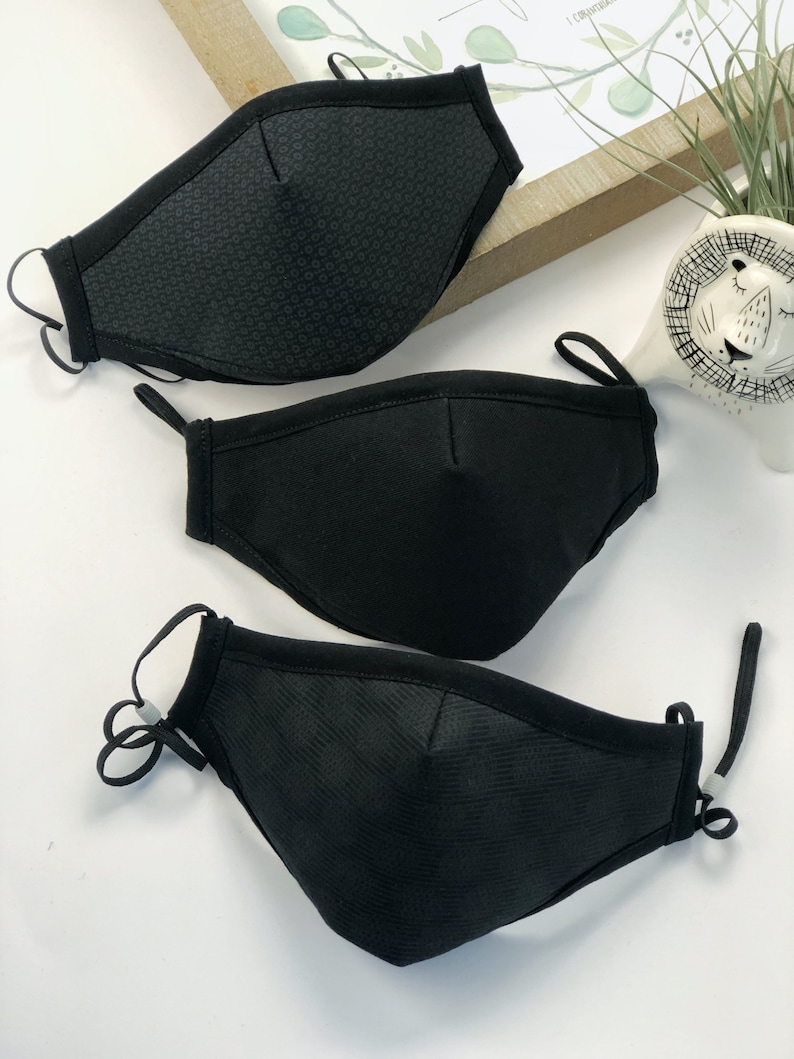 May include: Three black face masks with different patterns. The masks have elastic ear loops and a wire nose piece.