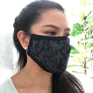 May include: A black face mask with a floral pattern. The mask is made of a soft, breathable fabric and has adjustable ear loops.
