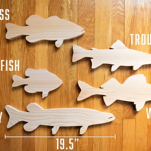 May include: Five wooden fish shapes, labeled "Bass", "Panfish", "Trout", "Walleye", and "Musky". The fish are arranged in a row on a wood floor. A ruler measures 19.5 inches.