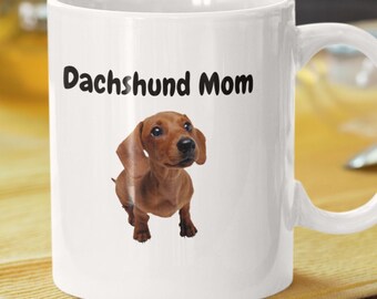 Op de afbeelding: Witte keramische koffiemok met een bruine teckel-illustratie en de tekst "Dachshund Mom" in zwart gedrukt.