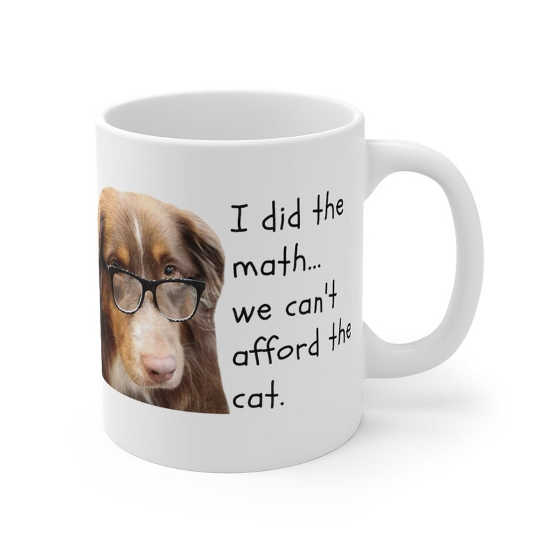 Puede incluir: Taza de caf&eacute; de cer&aacute;mica blanca con un perro marr&oacute;n y blanco que lleva gafas. La taza tiene el texto "Hice las cuentas... no podemos permitirnos el gato." impreso en ella.