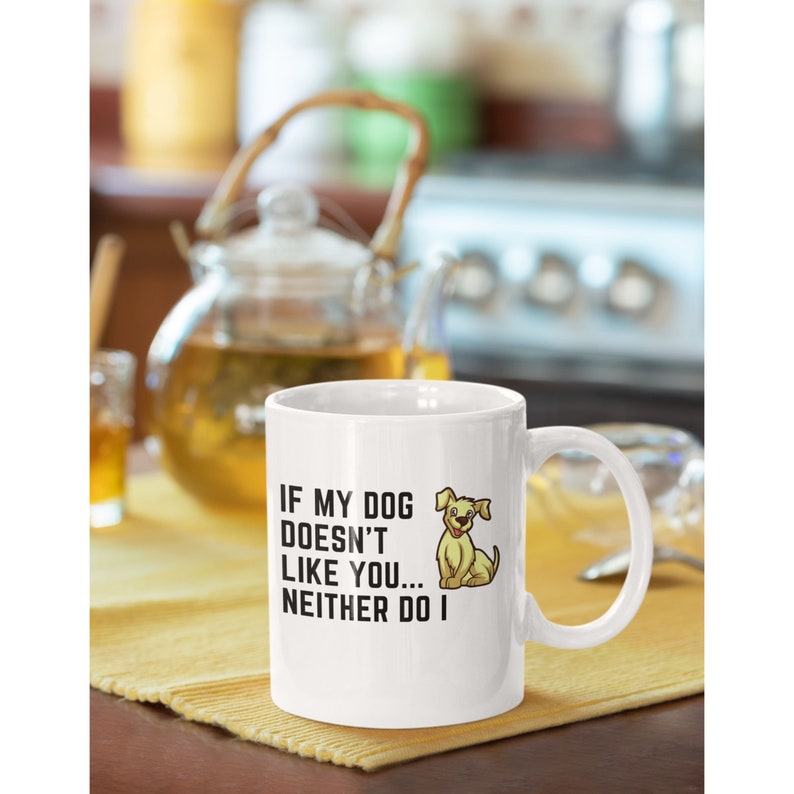 May include: White ceramic coffee mug with a black graphic that reads "If my dog doesn't like you... neither do I". A cartoon image of a yellow dog is next to the text.
