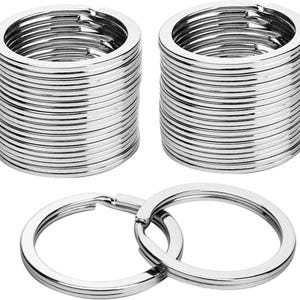 May include: A collection of silver-colored key rings. Two stacks of key rings are visible, along with two interlocked rings at the bottom. The rings are made of metal and have a circular shape.