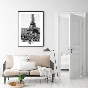 May include: Black and white framed print of the Eiffel Tower in Paris, France. The print features the iconic landmark against a cityscape background. The word "PARIS" is printed at the bottom of the image.