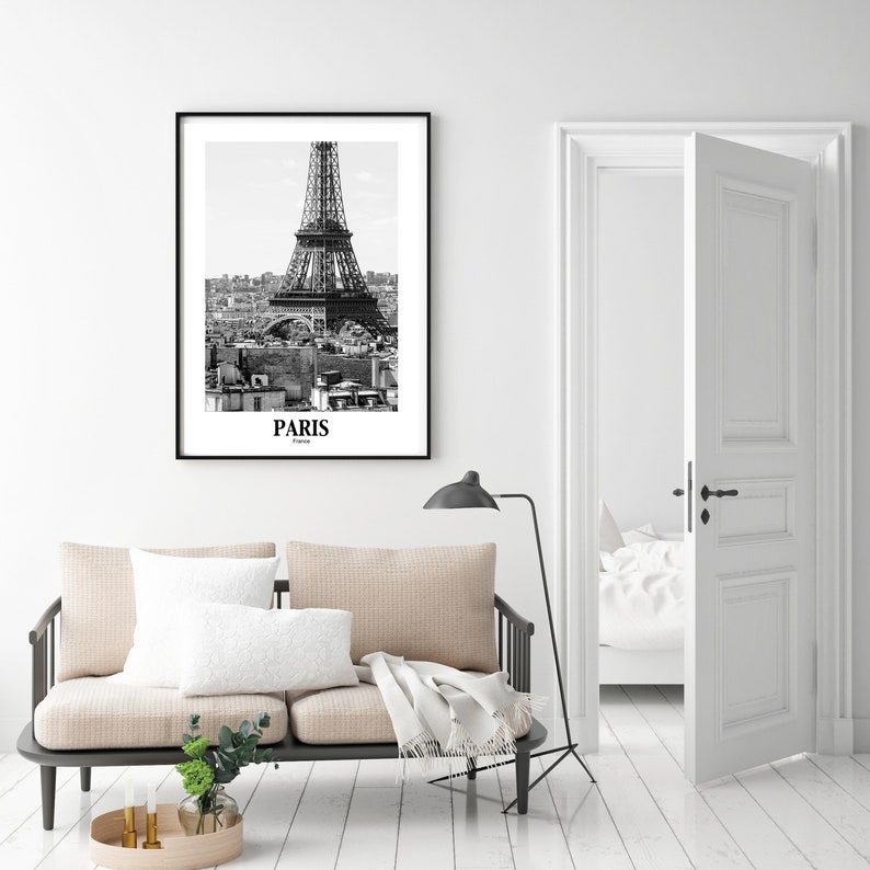 May include: Black and white framed print of the Eiffel Tower in Paris, France. The print features the iconic landmark against a cityscape background. The word "PARIS" is printed at the bottom of the image.