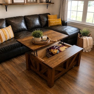 May include: A rectangular wooden coffee table with a lift-top mechanism that reveals an interior storage compartment. The table features a dark brown finish, X-shaped side supports, and a smooth top surface holding a round tray with a plant.