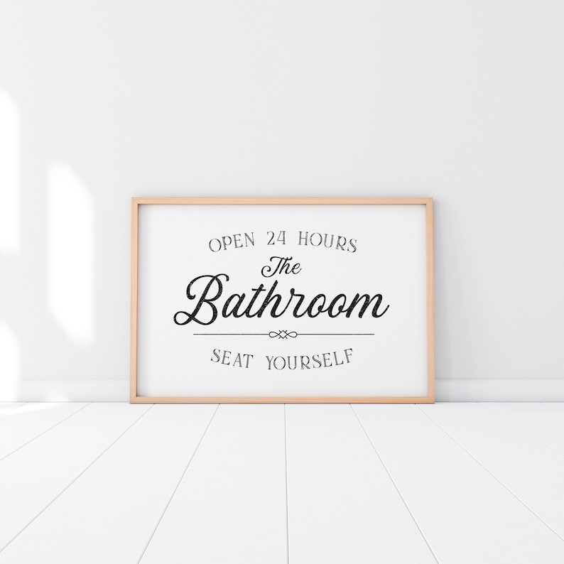 May include: A framed sign with the text "Open 24 Hours The Bathroom Seat Yourself" in black lettering on a white background.