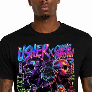 K&ouml;nnte beinhalten: Ein schwarzes T-Shirt mit einem lebendigen, mehrfarbigen Grafikdruck von Usher und Chris Brown. Das Design enth&auml;lt den Text "USHER X CHRIS BROWN", "Yeah Yeah Yeah Usher" und "All I want is a Confession" mit stilisierten Portr&auml;ts und Kronen.