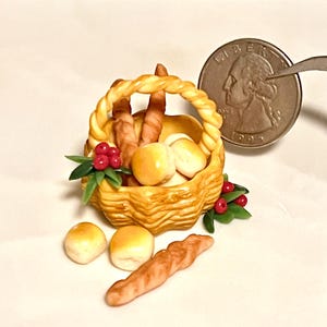May include: A miniature wicker basket filled with miniature bread rolls and croissants. The basket is decorated with red berries and green leaves.