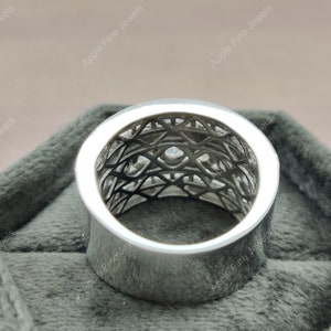 May include: A silver ring with a geometric design and small clear stones. The ring is in a gray velvet box.