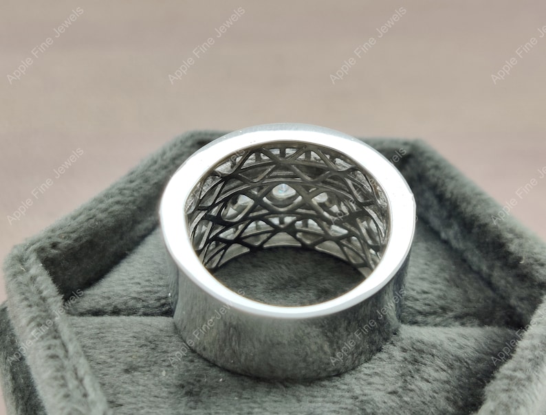 May include: A silver ring with a geometric design and small clear stones. The ring is in a gray velvet box.