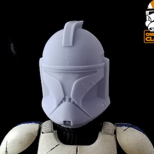 May include: A white and blue plastic clone trooper helmet with a gray face mask. The helmet is unpainted and has a textured surface.  ONE SIXTH CLONES is printed on the image.