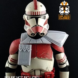 Puede incluir: Un conjunto de armadura de soldado clon de Star Wars a escala 1/6 en rojo y blanco con una hombrera gris y un casco rojo y blanco. La armadura est&aacute; desgastada y tiene un aspecto desgastado. "ONE SIXTH CLONES" est&aacute; impreso en la imagen.