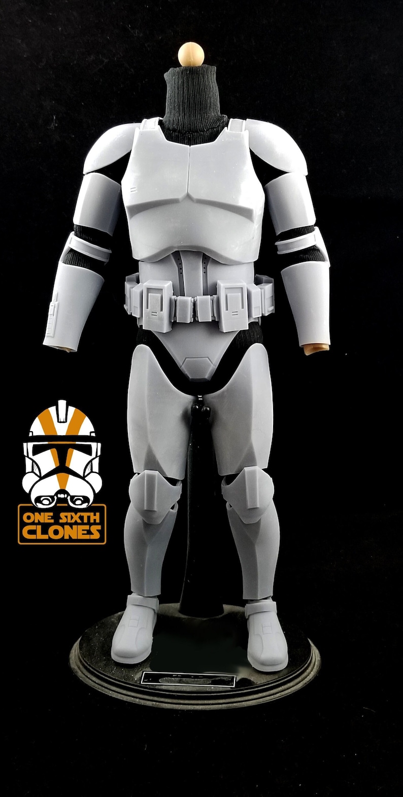 May include: A white plastic action figure of a Star Wars clone trooper wearing a black turtleneck. The figure is standing on a black circular base. The figure is wearing a white helmet with orange markings. The figure is holding a blaster rifle.