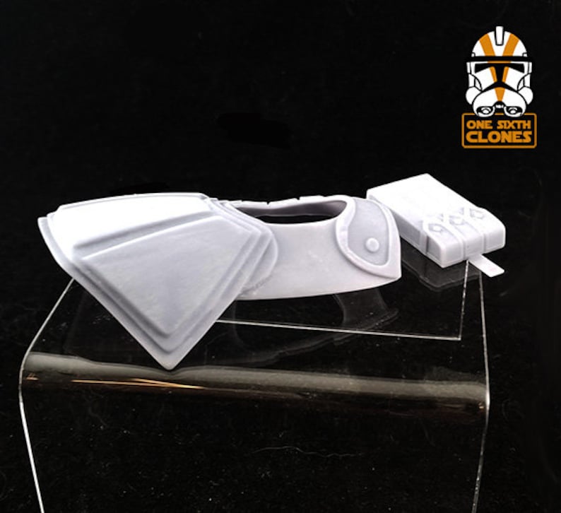 Puede incluir: Un modelo impreso en 3D de pl&aacute;stico blanco de una armadura de soldado clon de Star Wars, que incluye una pieza de pecho y un cintur&oacute;n de utilidad. El modelo est&aacute; en un soporte de exhibici&oacute;n de pl&aacute;stico transparente. La imagen tambi&eacute;n incluye un logotipo para "One Sixth Clones".
