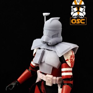 May include: A white plastic action figure of a Star Wars clone trooper with a red and white striped chest and arms. The figure has a white helmet with a red and white stripe on the side. The figure is wearing a white belt with a red and white stripe on the side.