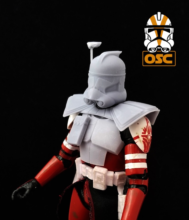 May include: A white plastic action figure of a Star Wars clone trooper with a red and white striped chest and arms. The figure has a white helmet with a red and white stripe on the side. The figure is wearing a white belt with a red and white stripe on the side.