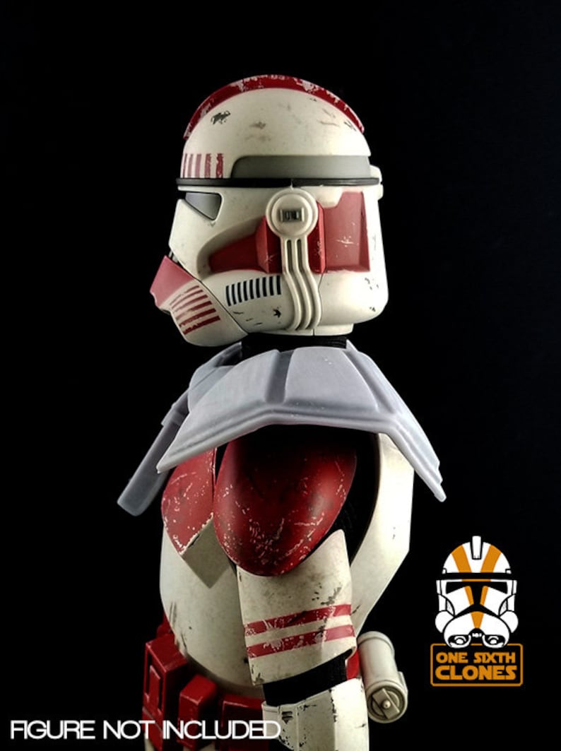 Puede incluir: Un casco de soldado clon de Star Wars blanco y rojo con un acabado de pintura desgastado y descolorido. El casco tiene una visera roja y una protecci&oacute;n de cuello gris. El casco es parte de una figura de acci&oacute;n a escala 1/6.